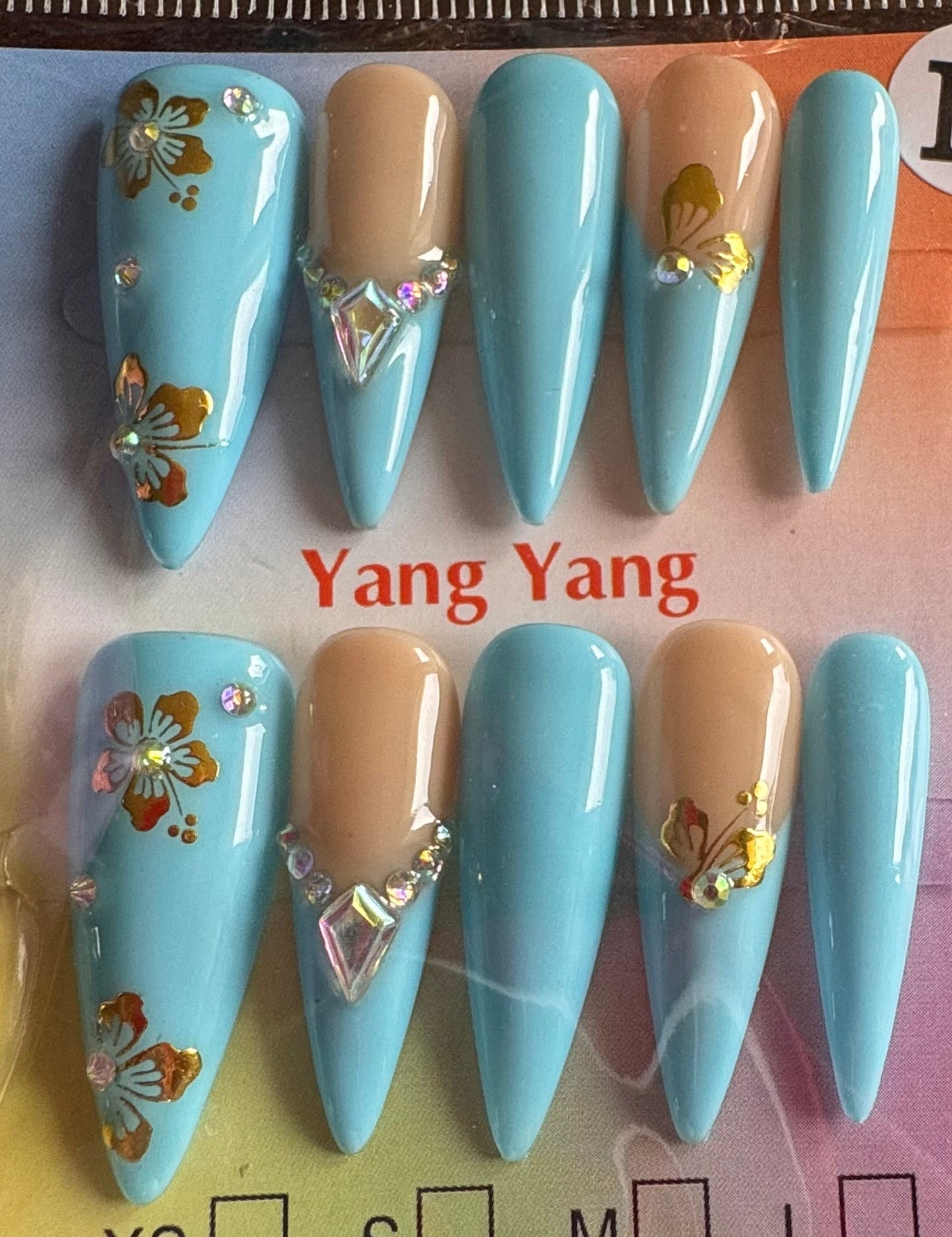 Set of blue and beige false nails with floral designs on a branded card.