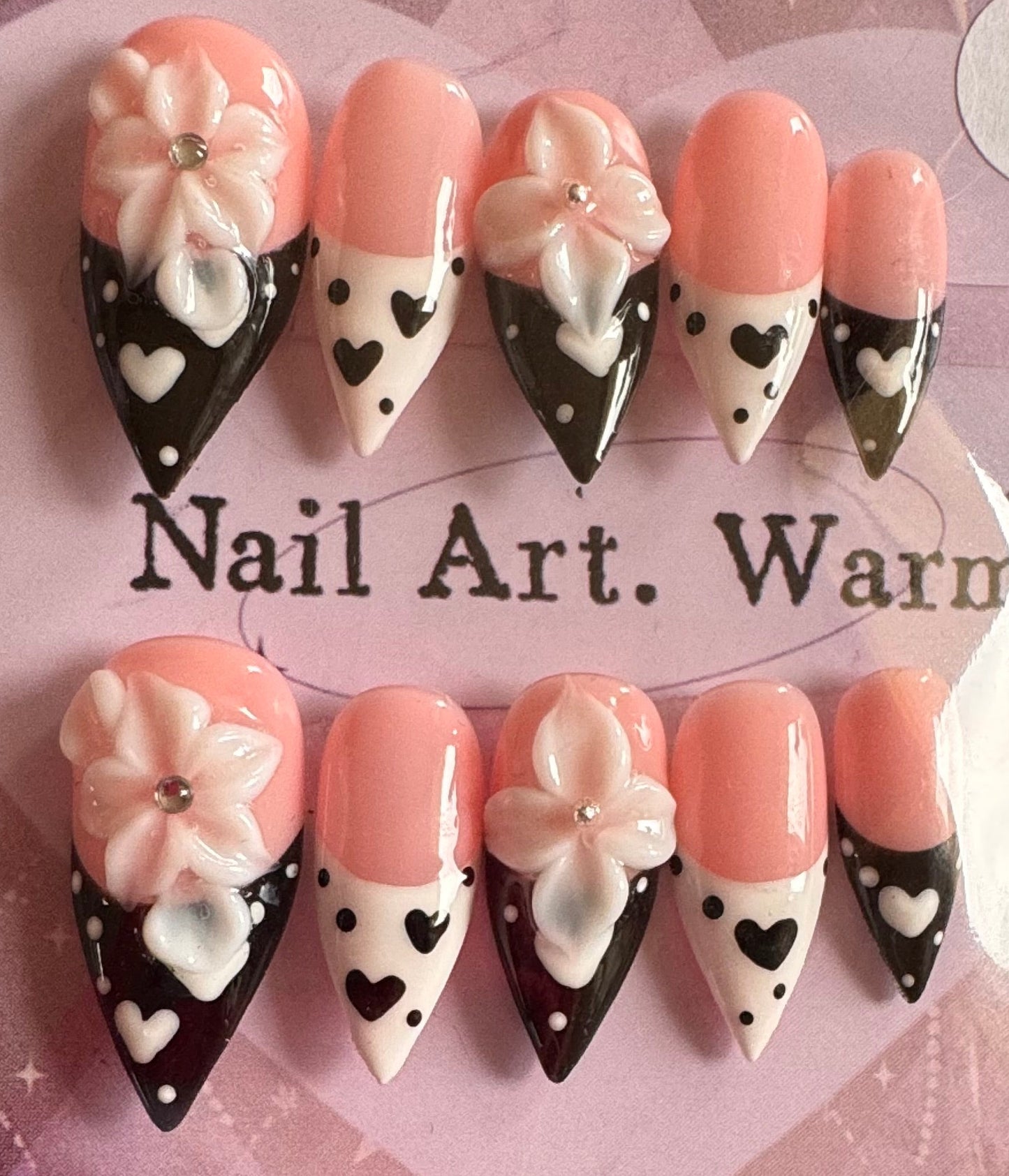 Set of decorative nail art tips with flowers and hearts on a branded card.