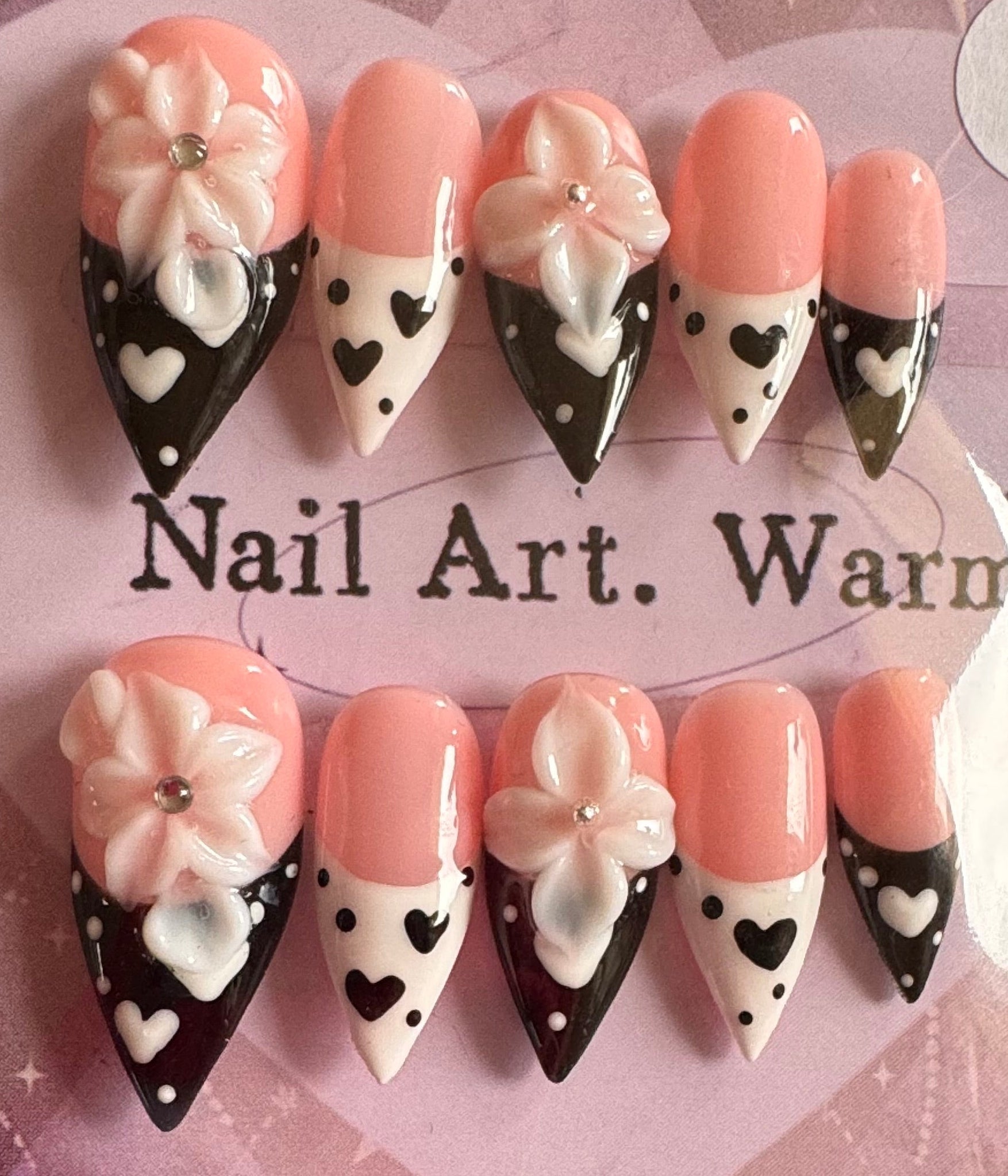 Set of decorative nail art tips with flowers and hearts on a branded card.
