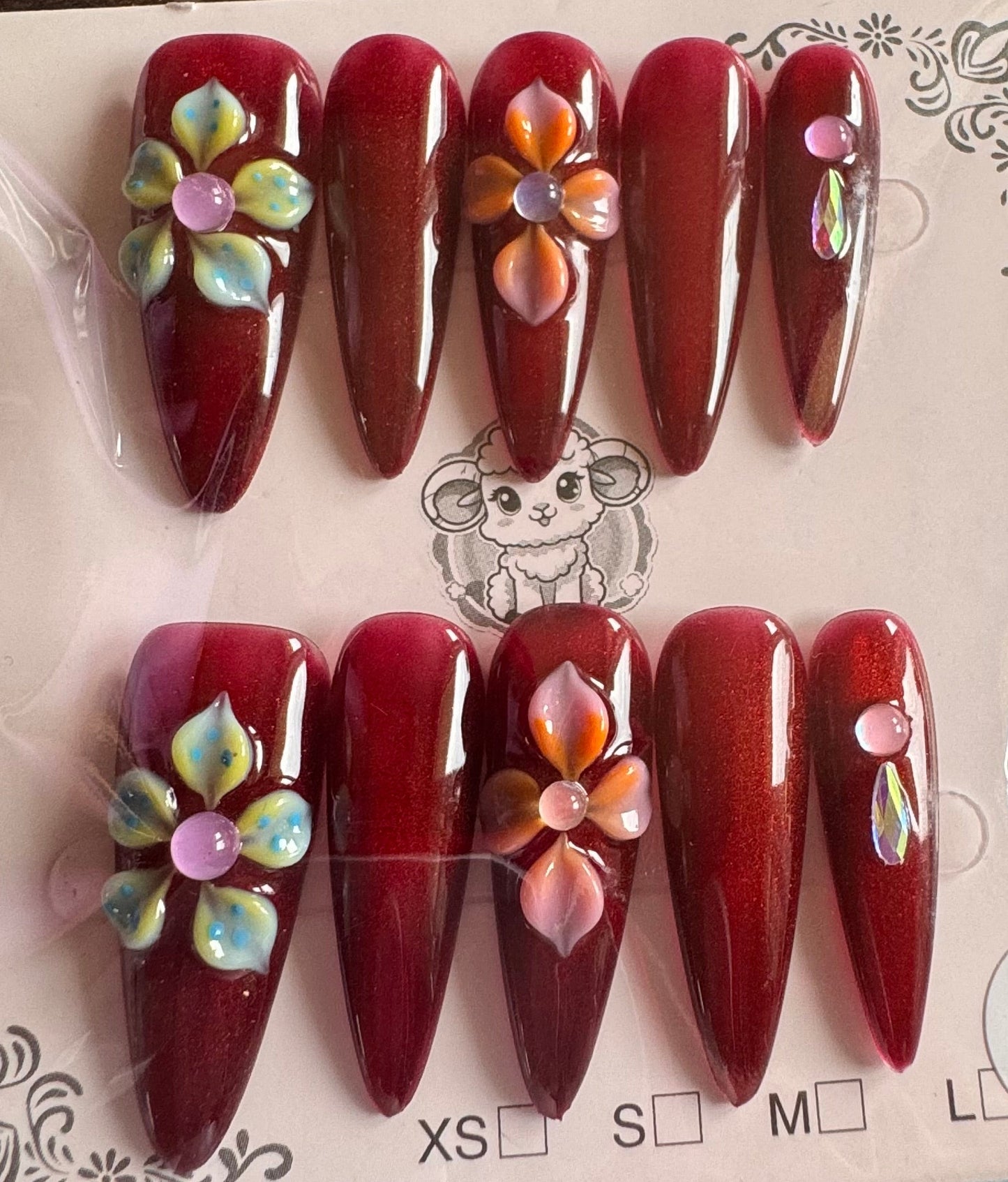Set of red nail art designs with flowers on a clear plastic card.