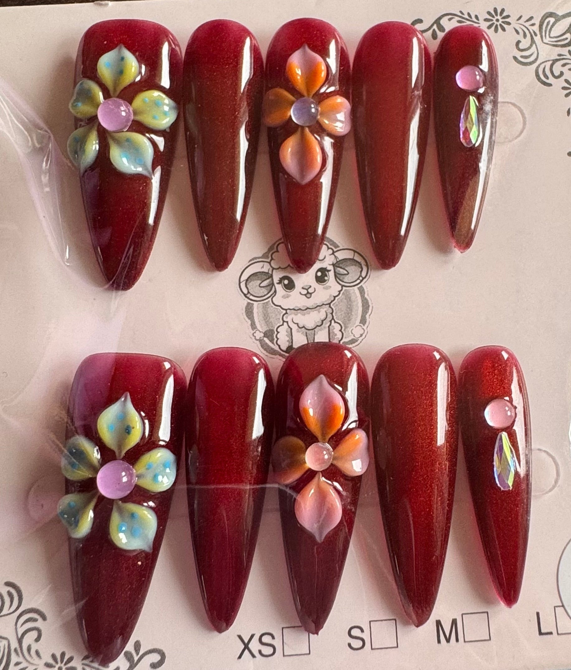 Set of red nail art designs with flowers on a clear plastic card.